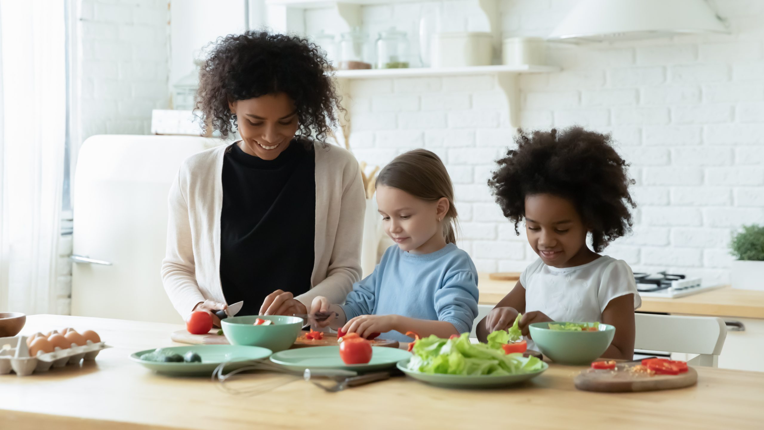 African mum two daughters cutting fresh vegetables preparing salad